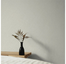 Vliestapete mit feiner Leinenstruktur in einem minimalistischen Raum mit Holztisch und Vase.