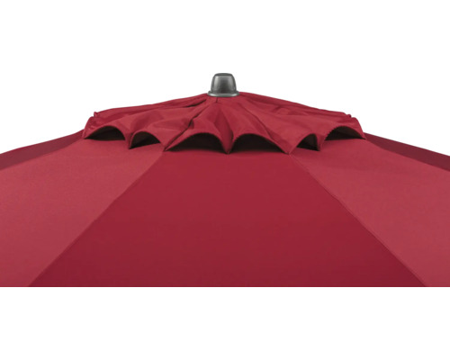 Nahaufnahme eines roten Sonnenschirms mit Windöffnung und einer dunklen Abdeckkappe an der Spitze.