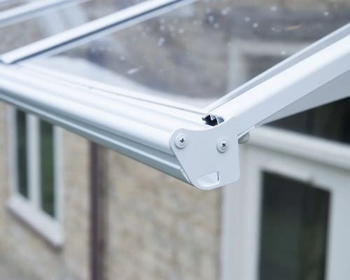 Detailaufnahme einer weißen Aluminium-Terrassenüberdachung mit Regenrinne, Endkappe und transparenter Eindeckung.