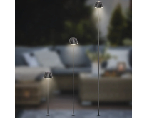 Drei verschieden hohe LED-Erdspießleuchten für den Garten mit plissierten Lampenschirmen in einem stimmungsvollen Außenbereich.