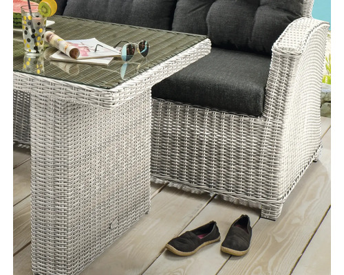 Gartenmöbel Set aus hellem Polyrattan Geflecht mit Glastisch und Lounge Sessel mit dunklen Kissen auf einer Holzterrasse.