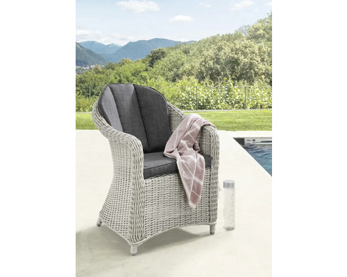 Gartenstuhl aus grauem Polyrattan mit dunklen Sitzkissen auf einer Terrasse am Pool vor einer hellen, weitläufigen Hügellandschaft.
