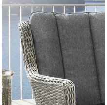 Nahaufnahme eines Gartenstuhls aus Polyrattan mit grauem Polster auf einem Balkon.