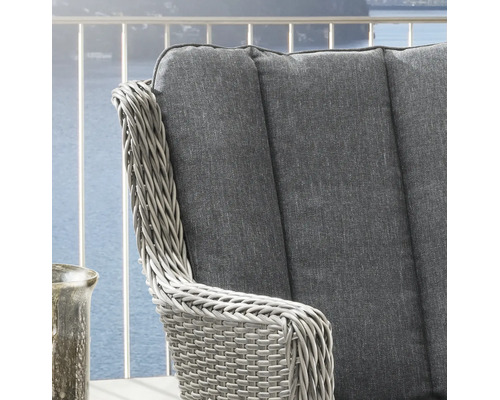 Nahaufnahme eines Gartenstuhls aus Polyrattan mit grauem Polster auf einem Balkon.