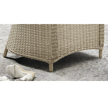 Nahaufnahme eines Gartenmöbels aus Polyrattan-Geflecht mit geflochtenen Füßen auf einem Steinboden.