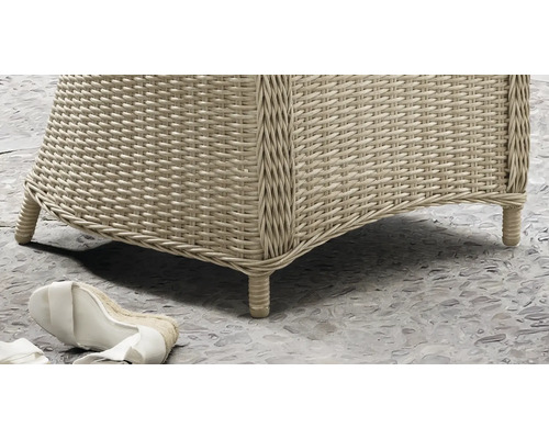 Nahaufnahme eines Gartenmöbels aus Polyrattan-Geflecht mit geflochtenen Füßen auf einem Steinboden.