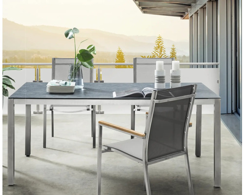 Moderne Garten-Essgruppe auf Balkon mit rechteckigem Tisch, grauer Platte, Metallgestell und grauen Netzstühlen mit Holzarmlehnen.