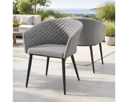 Zwei grau gepolsterte Sessel mit Rautensteppung und schwarzen Metallbeinen auf einer Terrasse in einer hellen Gartenlandschaft.