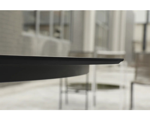 Nahaufnahme der schmalen schwarzen Tischkante eines Gartentischs im Außenbereich.