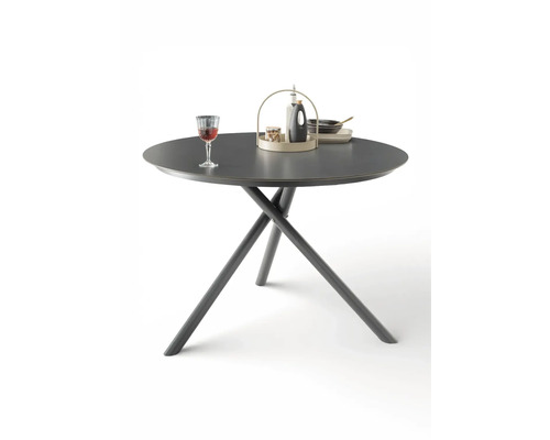 Runder Esstisch in Anthrazit mit gekreuzten Tischbeinen, dekoriert mit einem Weinglas und einem Serviertablett.