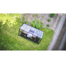 Draufsicht auf ein rechteckiges Gewächshaus mit Metallrahmen und Glaspaneelen auf einer Rasenfläche im Garten.