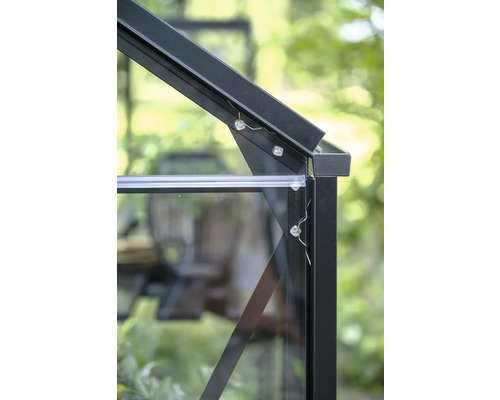 Detailaufnahme einer Eckverbindung am Gewächshausrahmen aus schwarzem Aluminium mit Glasscheiben und Befestigungsschrauben.