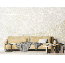 Fototapete mit filigranem Blattstruktur-Motiv in einem hellen Wohnzimmer hinter einem Sofa mit Kissen und Beistelltischen.