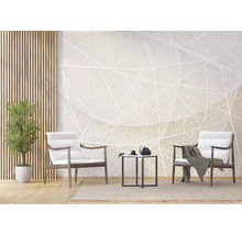 Helles Wohnzimmer mit Fototapete im Blattadern-Design, zwei Holzsesseln mit weißen Polstern, schwarzem Beistelltisch und Zimmerpflanze.