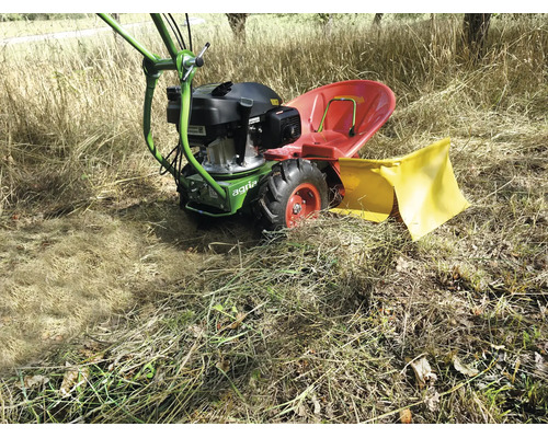 Agria Motormäher mit rotem Sitz und gelber Schutzabdeckung im Einsatz auf einer hellen Wiese mit hohem, trockenem Gras.