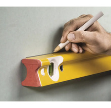 Eine Hand zieht mit einem Bleistift eine Linie an einer Stabila Wasserwaage entlang an einer Wand.