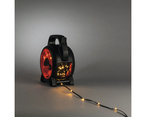 Schwarze und rote Kabeltrommel für Lichterketten aus Kunststoff mit Tragegriff, Kurbel und warmweißer LED-Lichterkette.