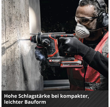 Eine Person verwendet einen Einhell Akku Bohrhammer an einer Betonwand und trägt dabei Schutzbrille, Atemschutzmaske, Gehörschutz und Handschuhe.