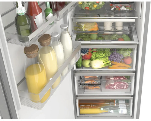 Gut organisierter, offener Kühlschrank mit Obst, Gemüse, Fleisch und Getränken in verschiedenen Frischefächern und Türabstellern.