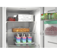 Gut organisierter Gefrierschrank mit Pizzakartons, Lasagneform und Eis am Stiel. Helle Innenbeleuchtung und Glasablagen.
