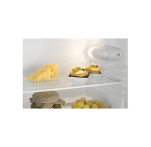Innenansicht eines Kühlschranks mit Glasablagen, Käse, Törtchen und Weintrauben. Helle Beleuchtung und Temperaturregler sind sichtbar.