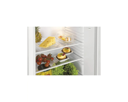 Offener Kühlschrank mit Glasablagen, gefüllt mit frischen Lebensmitteln wie Käse, Tomaten, Obsttörtchen und Salat.