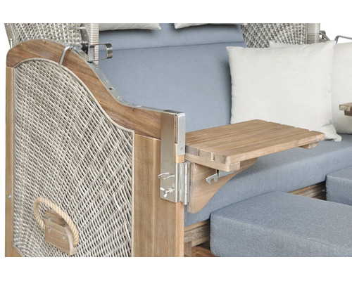 Detail eines Strandkorbs mit ausgeklapptem Seitentisch aus Holz, Geflecht und grauen Polstern.