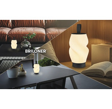 Tragbare LED-Tischleuchte von Briloner mit gedrehtem Schirm und Griff in Wohnräumen auf Sofa, Tisch und Schreibtisch. Briloner Logo.