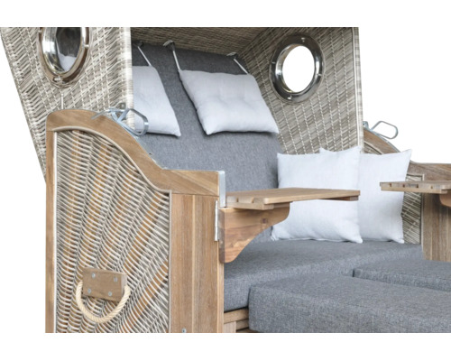 Strandkorb aus Geflecht und Holz mit Bullaugen, Klapptischen und Polstern.