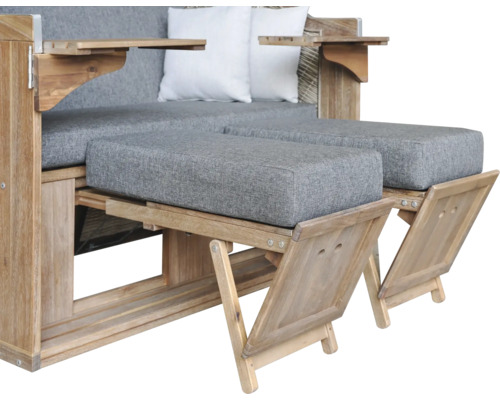 Strandkorb aus Holz mit grauen Polstern, zwei weißen Kissen und zwei ausziehbaren Fußstützen.