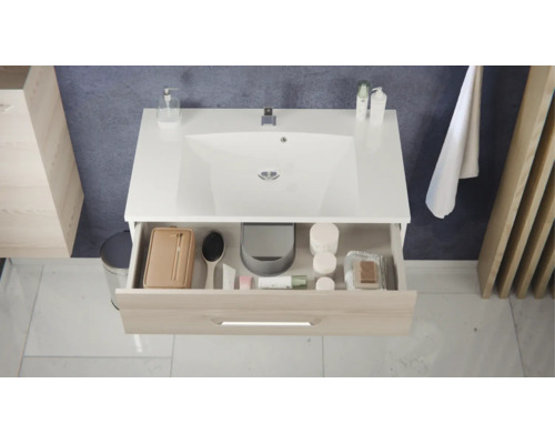 Moderner Waschbeckenunterschrank mit weißem Waschbecken und geöffneter Schublade in Holzoptik mit Badutensilien.