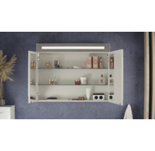 Geöffneter Badezimmer-Spiegelschrank mit integrierter LED-Beleuchtung, drei Glaseinlegeböden und diversen Kosmetikprodukten an einer Wand.