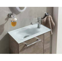 Moderner Waschtisch mit weißem Glasbecken, Unterschrank in Holzoptik, verchromter Armatur, Seifenspender und Handtuchhalter.