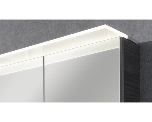Detailansicht eines Badezimmerspiegelschranks mit integrierter LED Beleuchtung an der Oberseite und dunkler Seitenwand.