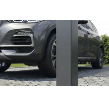 Nahaufnahme eines quadratischen Metallpfostens für ein Carport auf einer gepflasterten Einfahrt neben einem grauen Auto.