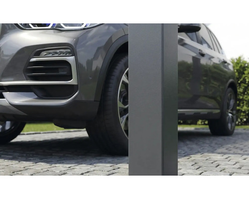 Nahaufnahme eines quadratischen Metallpfostens für ein Carport auf einer gepflasterten Einfahrt neben einem grauen Auto.
