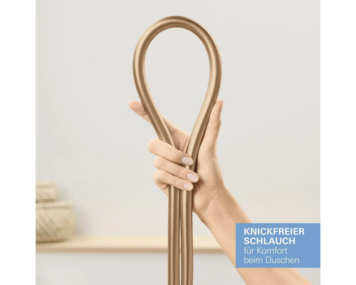 Hand hält einen goldfarbenen, knickfreien Brauseschlauch, der zu einer Schlaufe gebogen ist.
