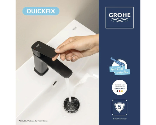 Hand bedient schwarze Grohe Waschtischarmatur auf weißem Becken. Symbole: QuickFix, Werkzeug, deutsches Design, fünf Jahre Garantie. Grohe Logo.
