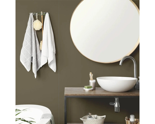 Modernes Badezimmer mit olivgrüner Wand, rundem Spiegel mit Holzrahmen, weißem Aufsatzwaschbecken auf einem Waschtisch aus Holz und Handtüchern.