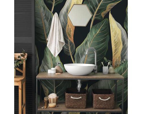 Fototapete mit großen botanischen Blättern im Badezimmer hinter einem Waschtisch aus Holz mit weißem Aufsatzwaschbecken und Zubehör.
