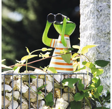 Gartenfigur Frosch mit Fernglas und gestreiftem Shirt auf einer Gabione mit Steinen inmitten grüner Pflanzen im Garten.