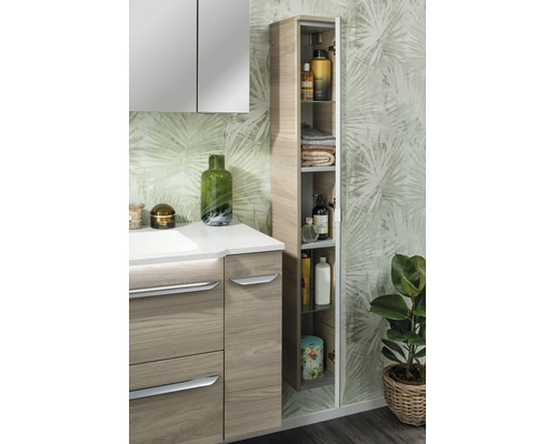 Modernes Badezimmer mit Waschtischunterschrank in Holzoptik, Spiegelschrank und offenem Hochschrank vor einer Tapete mit Blattmuster.
