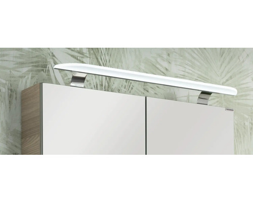 Weiße LED-Aufsatzleuchte für Badezimmerspiegel mit Metallhalterungen auf einem Spiegelschrank mit Fackelmann Logo.