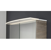 Spiegelschrank mit LED-Aufsatzleuchte und Korpus in Holzoptik.
