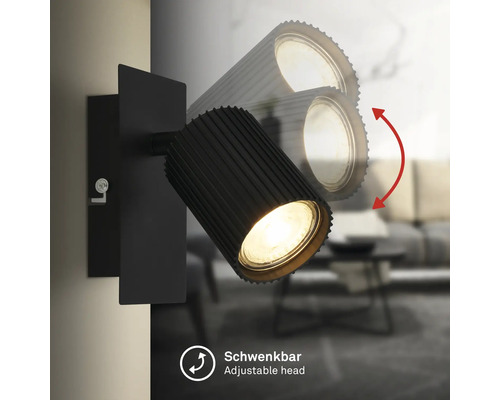 Schwarzer Wandstrahler mit schwenkbarem, geriffeltem Lampenkopf für gezielte Beleuchtung.
