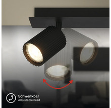 Schwenkbarer schwarzer Strahler mit geriffeltem Gehäuse, Darstellung der Schwenkfunktion des Lampenkopfes.