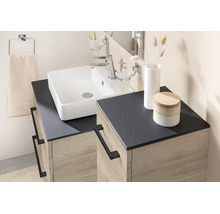 Modernes Badezimmer mit weißem Aufsatzwaschbecken, dunkler Arbeitsplatte und Unterschrank in Eichenoptik mit schwarzen Metallgriffen.
