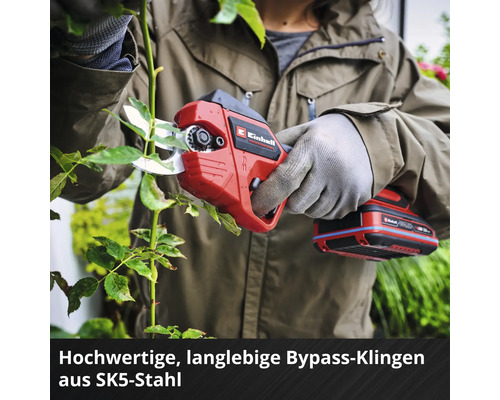 Einhell Akku-Astschere mit Bypass-Klingen aus SK5-Stahl beim Schneiden eines Pflanzenzweigs durch eine Person mit Handschuhen.