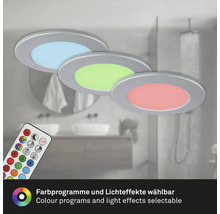 Drei runde LED Einbauleuchten mit Fernbedienung für verschiedene Farbprogramme und Lichteffekte vor einem Badezimmerhintergrund.