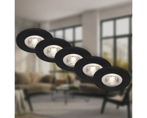 Fünf runde LED Einbaustrahler in moderner Optik vor einem unscharfen Wohnzimmerhintergrund.